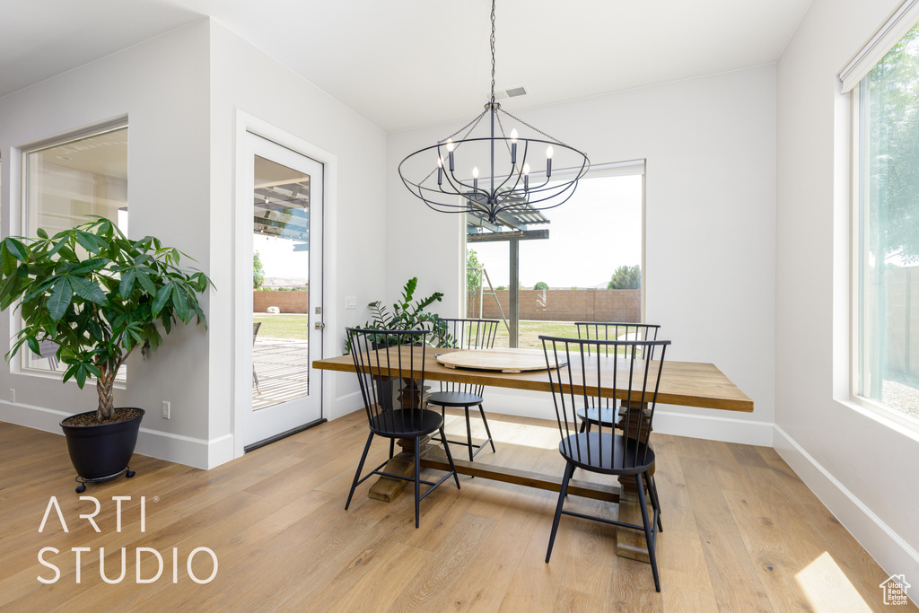 Dining room with a chandelier, baseboards, a wealth of natural light, and light wood finished floors