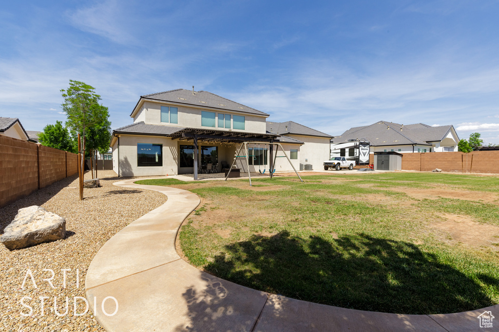 Rear view of house featuring a fenced backyard, stucco siding, a patio, a shed, and a pergola