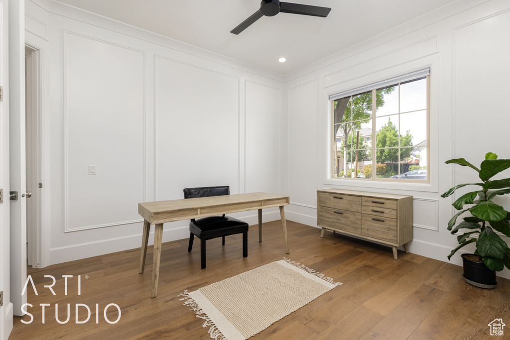 Office area with ornamental molding, a ceiling fan, wood finished floors, and a decorative wall