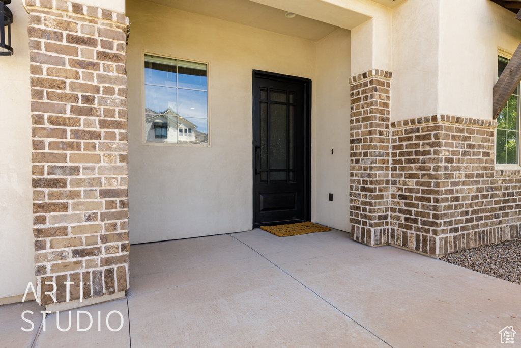 Doorway to property featuring brick siding and stucco siding