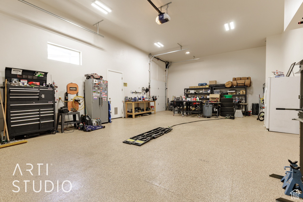 Garage with a workshop area, a garage door opener, and freestanding refrigerator