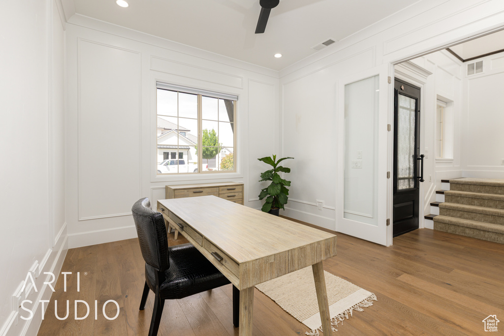 Office space featuring a ceiling fan, crown molding, and a decorative wall