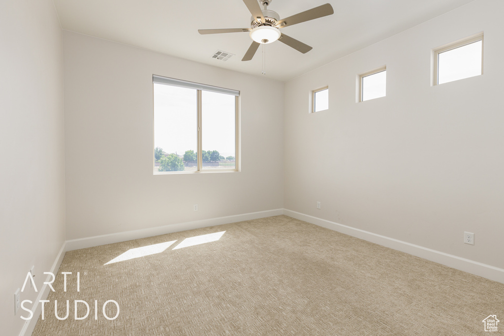 Carpeted empty room featuring baseboards, visible vents, and a ceiling fan