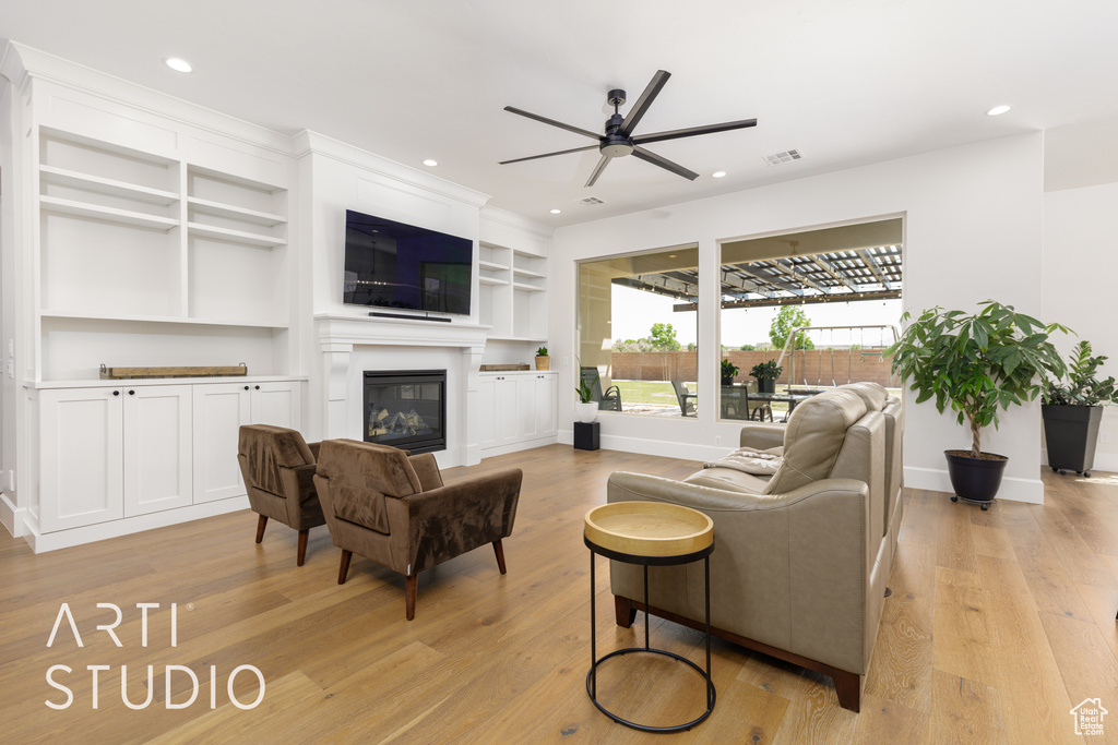 Living area featuring recessed lighting, a ceiling fan, light wood finished floors, and a glass covered fireplace