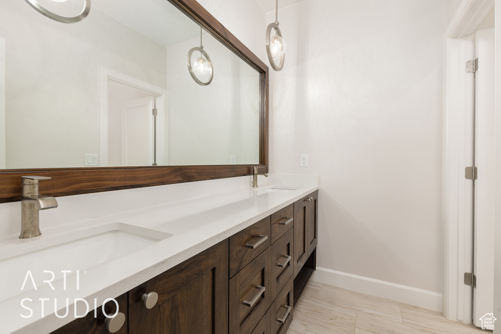 Bathroom featuring double vanity, baseboards, and a sink