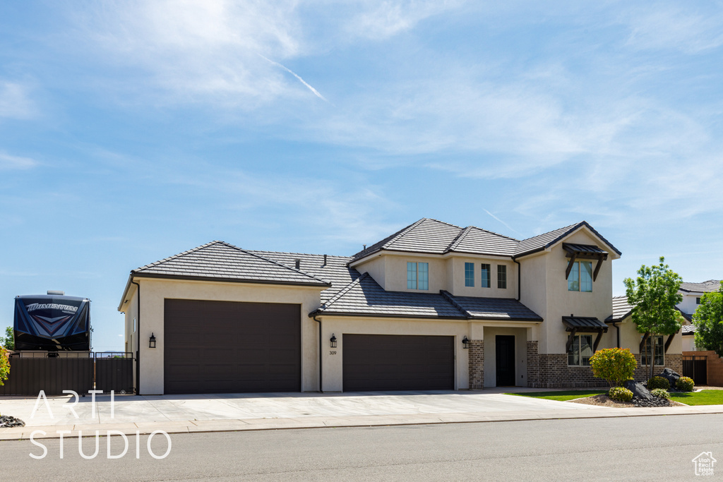View of front of house with a garage, fence, stucco siding, and driveway