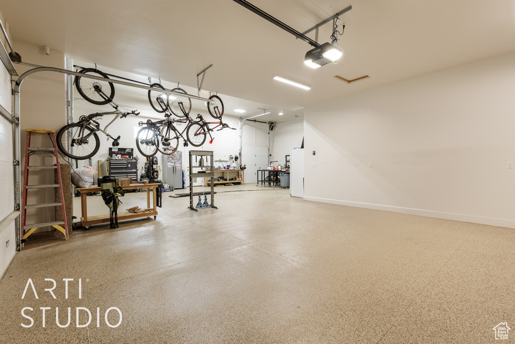 Garage featuring a workshop area, baseboards, and a garage door opener