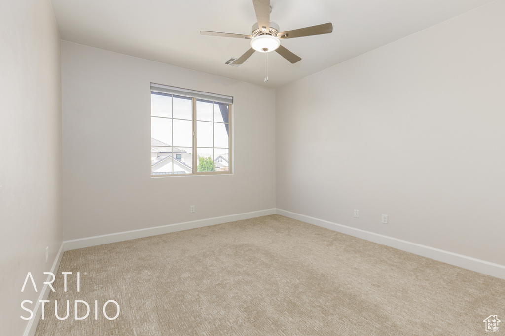 Carpeted spare room with ceiling fan and baseboards