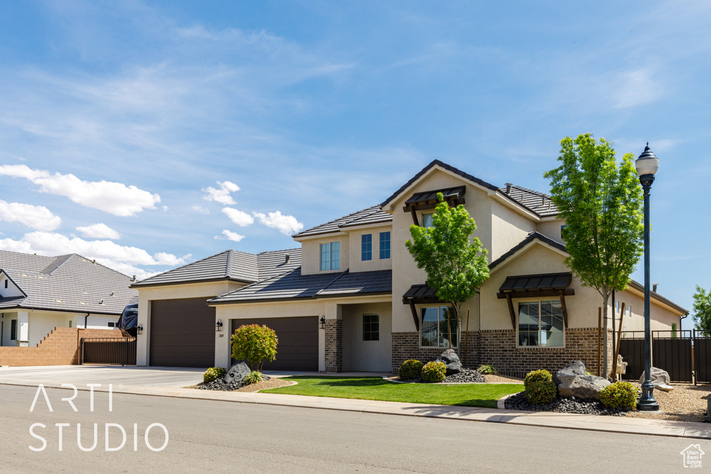 View of front of home featuring stucco siding, brick siding, fence, a garage, and concrete driveway