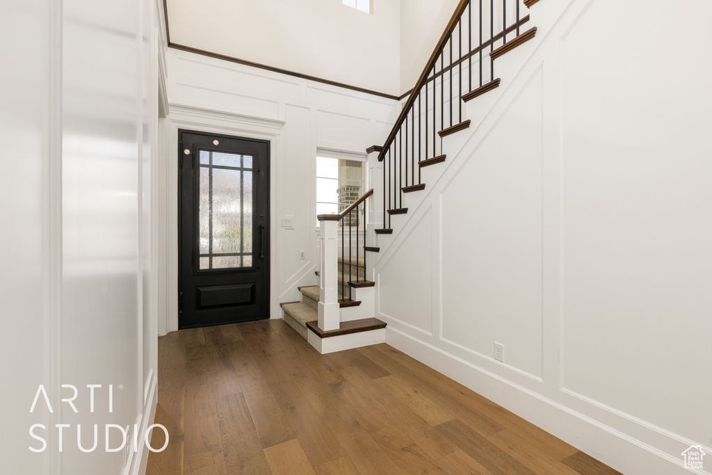 Foyer entrance with stairs, wood finished floors, a decorative wall, and plenty of natural light