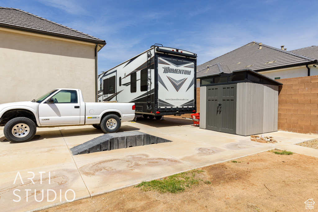 Exterior space featuring fence, a storage shed, stucco siding, and an outbuilding