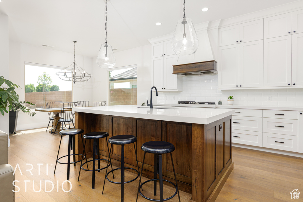 Kitchen with light wood finished floors, a sink, custom range hood, and plenty of natural light
