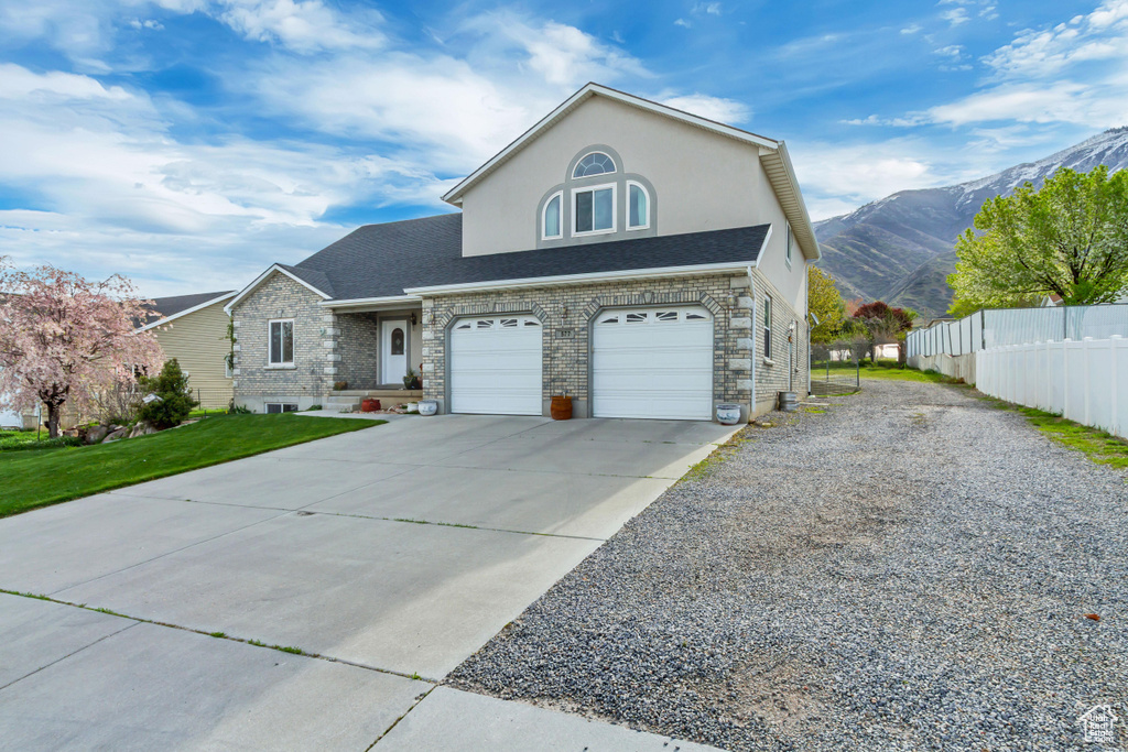 View of front of home with concrete driveway, stucco siding, a mountain view, an attached garage, and fence