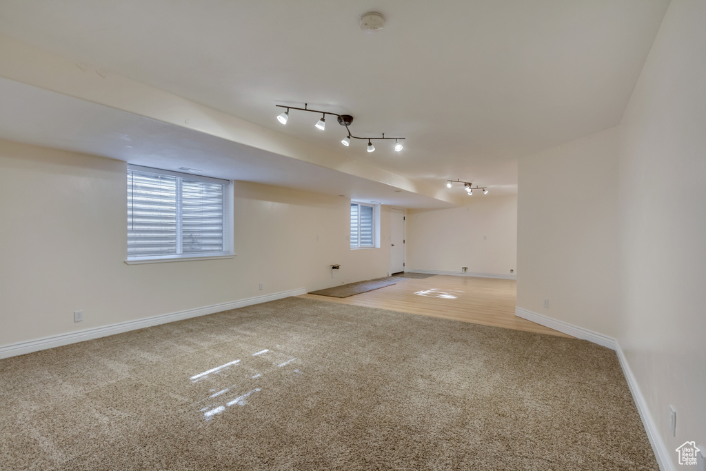 Basement featuring track lighting, carpet, and baseboards
