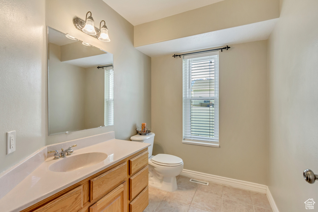 Bathroom featuring tile patterned floors, toilet, vanity, baseboards, and visible vents