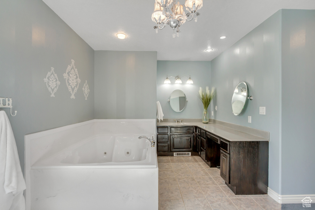 Full bath with a tub with jets, tile patterned flooring, vanity, baseboards, and a notable chandelier