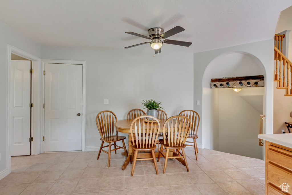 Dining area with ceiling fan, baseboards, arched walkways, and stairs