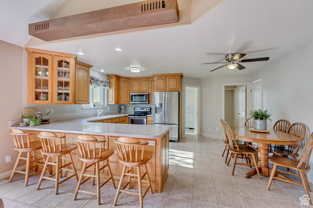 Kitchen with glass insert cabinets, a sink, appliances with stainless steel finishes, baseboards, and a peninsula