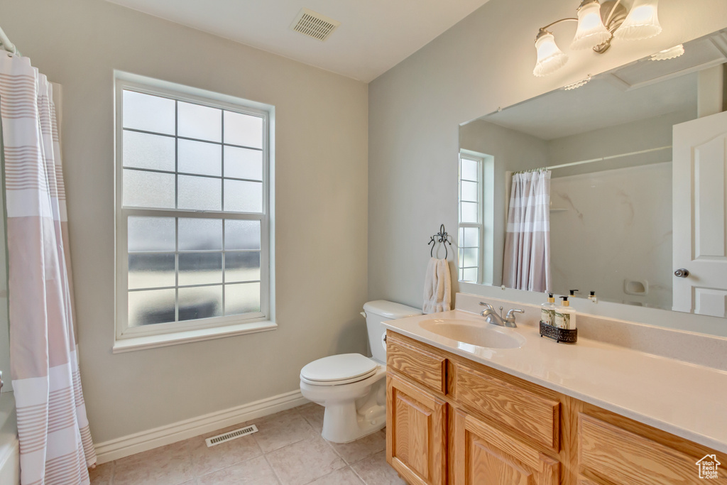 Bathroom with vanity, toilet, visible vents, baseboards, and tile patterned flooring