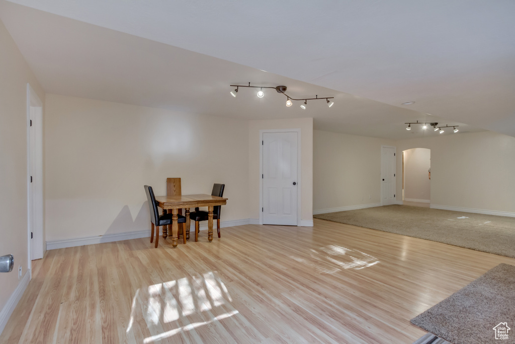 Dining room with arched walkways, rail lighting, wood finished floors, and baseboards