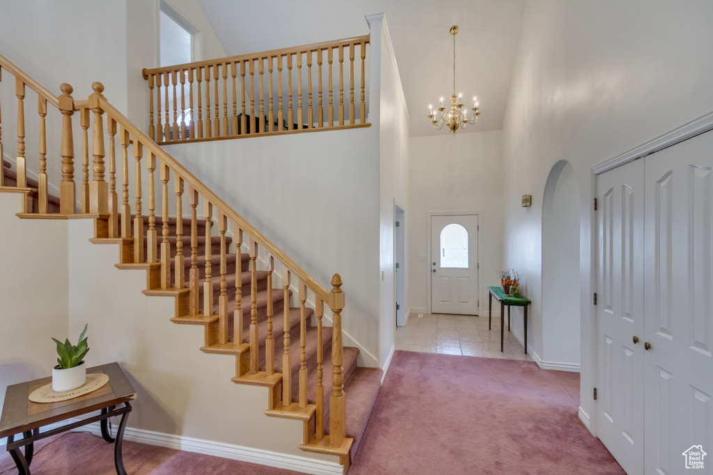 Carpeted entrance foyer featuring baseboards, arched walkways, stairs, and a high ceiling