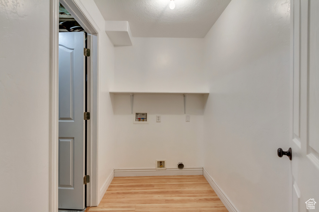 Laundry room featuring light wood finished floors, hookup for an electric dryer, washer hookup, laundry area, and baseboards