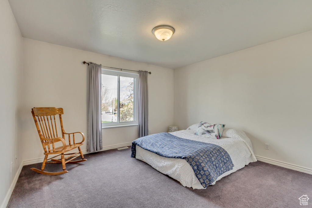 Bedroom with dark colored carpet and baseboards