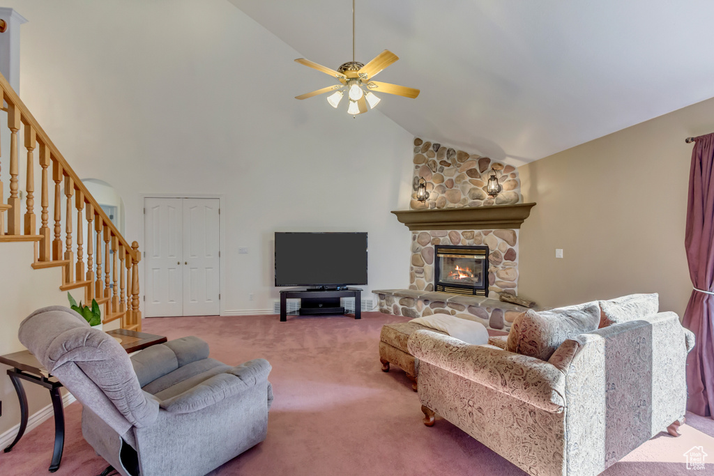 Carpeted living area with stairs, high vaulted ceiling, ceiling fan, and a fireplace
