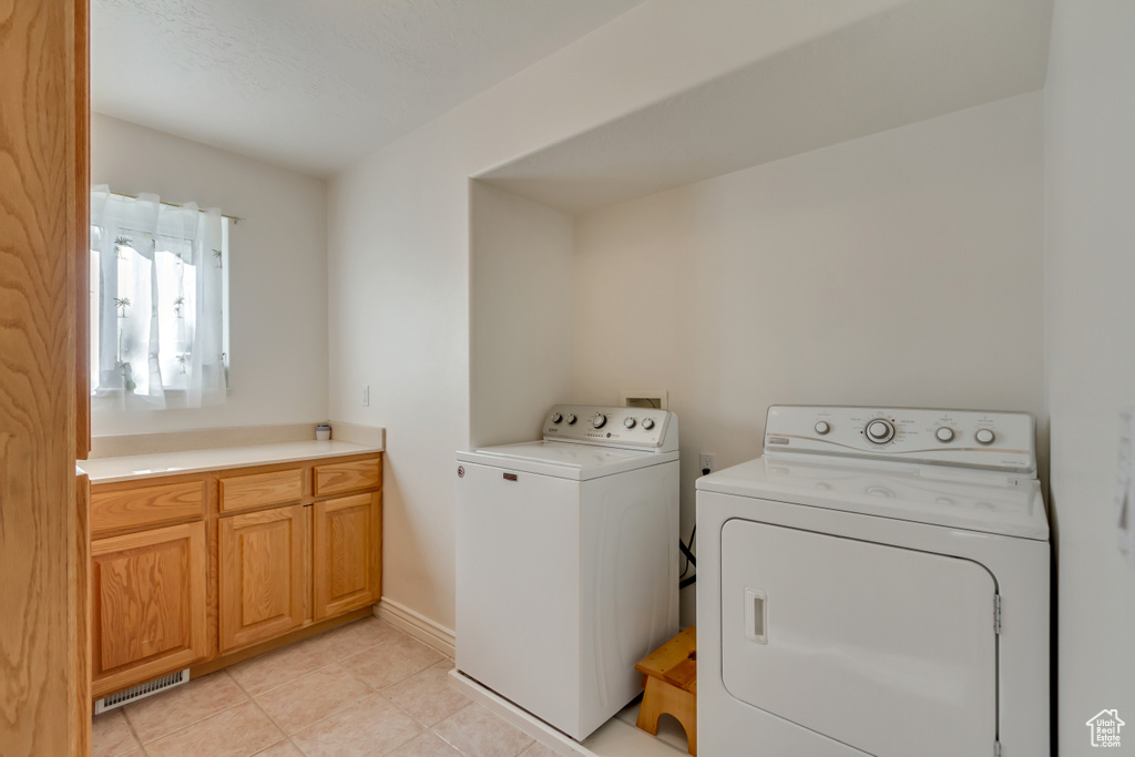 Washroom with light tile patterned floors, cabinet space, visible vents, and independent washer and dryer