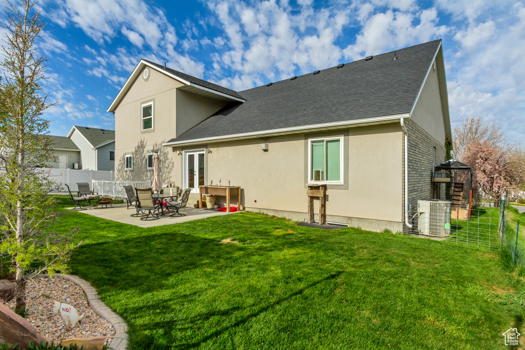 Back of property featuring a patio, stucco siding, central air condition unit, fence, and french doors