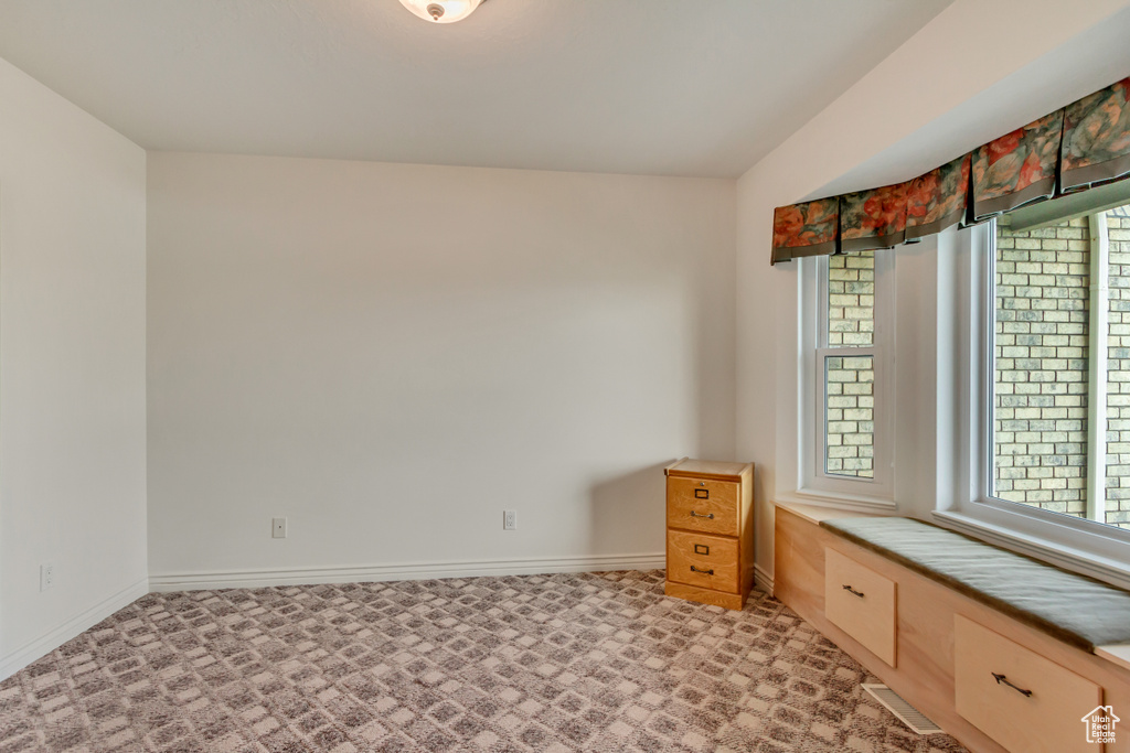 Empty room with light colored carpet and baseboards