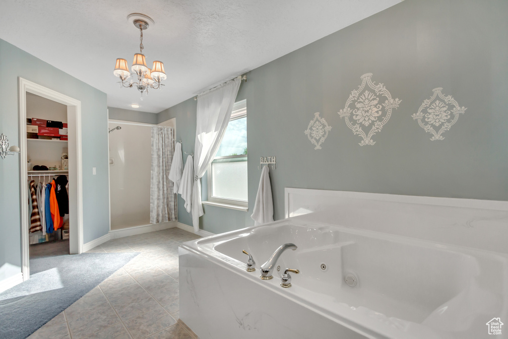 Bathroom featuring a shower stall, tile patterned floors, a chandelier, a tub with jets, and a spacious closet