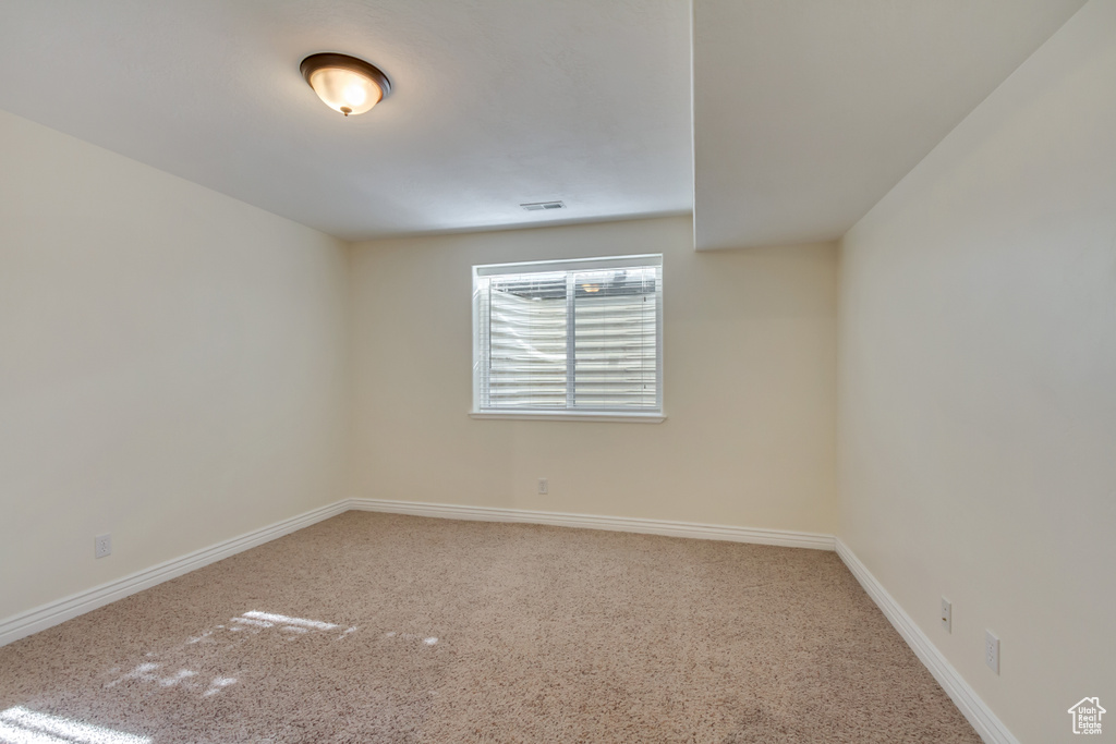 Empty room featuring carpet flooring, visible vents, and baseboards