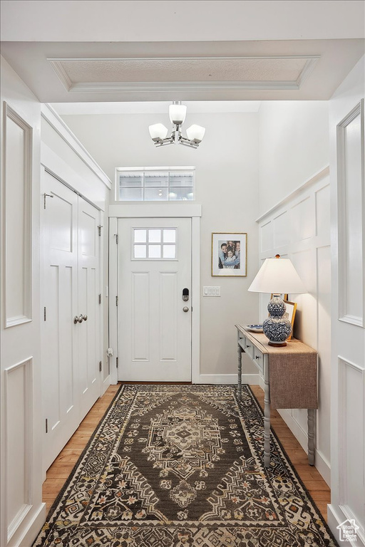 Entryway featuring ornamental molding, a chandelier, and light wood-style floors