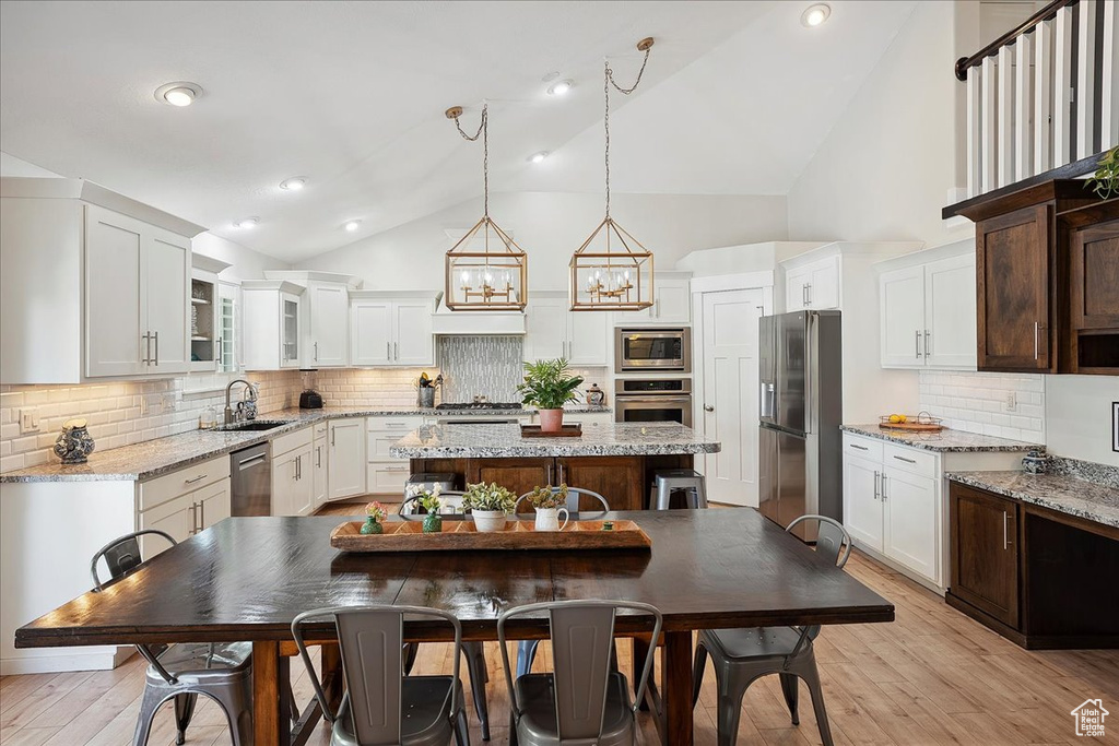 Kitchen with a sink, decorative backsplash, a center island, white cabinets, and appliances with stainless steel finishes