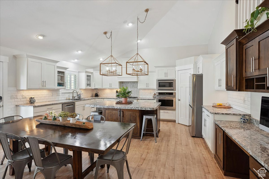 Kitchen with backsplash, white cabinets, appliances with stainless steel finishes, and a kitchen island
