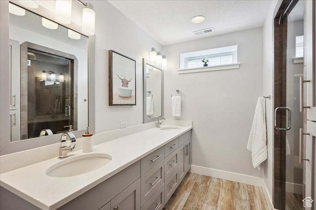 Full bath with a sink, visible vents, a shower stall, and wood finished floors