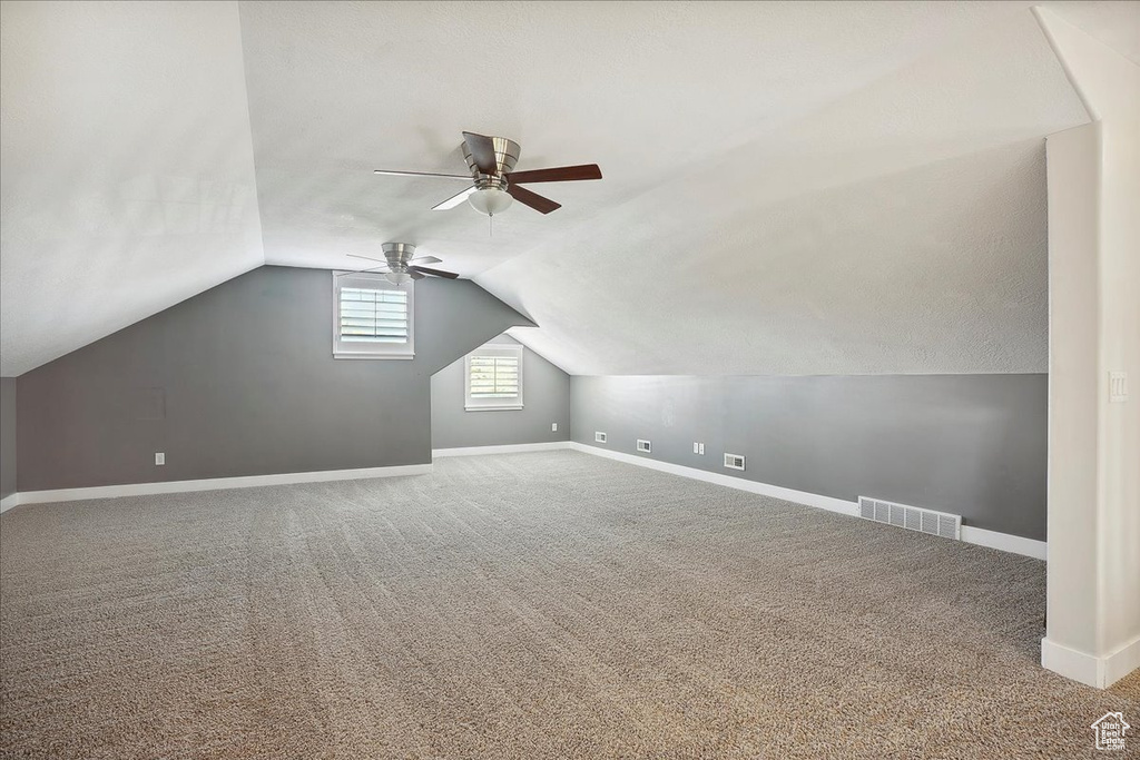 Additional living space featuring a ceiling fan, visible vents, vaulted ceiling, carpet, and baseboards