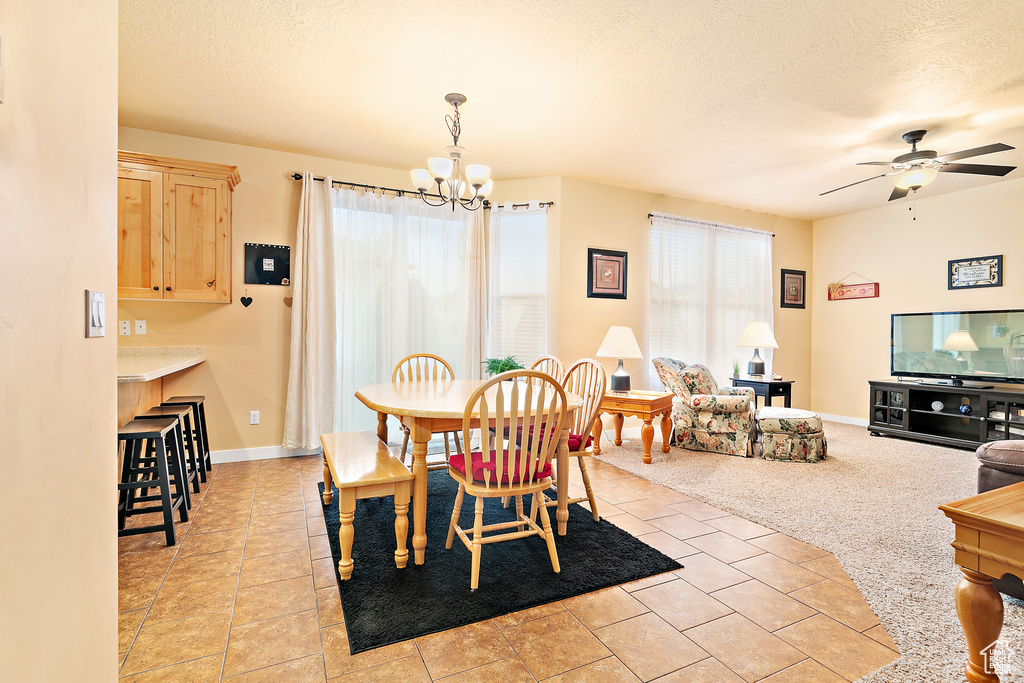 Dining area featuring a textured ceiling, baseboards, and ceiling fan with notable chandelier
