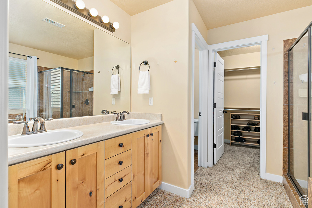 Full bathroom featuring a sink, a stall shower, double vanity, and visible vents