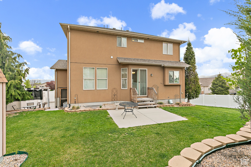 Rear view of house with fence, stucco siding, a yard, and a patio area