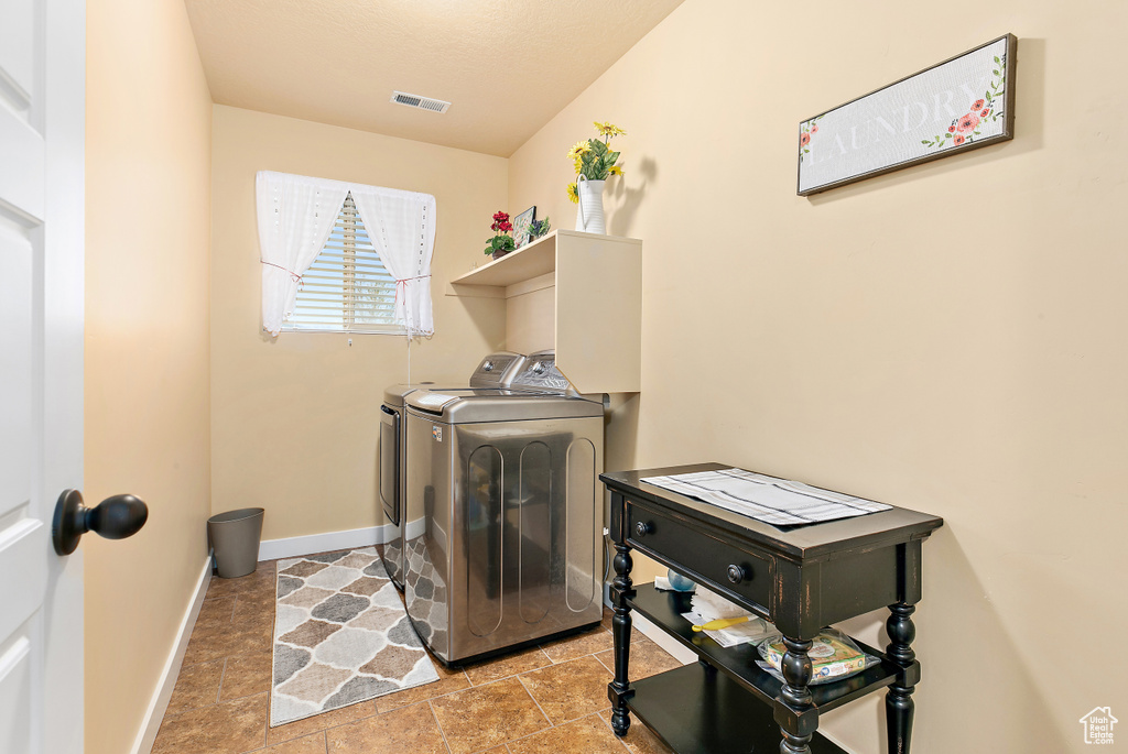 Clothes washing area with washer and dryer, visible vents, laundry area, and baseboards