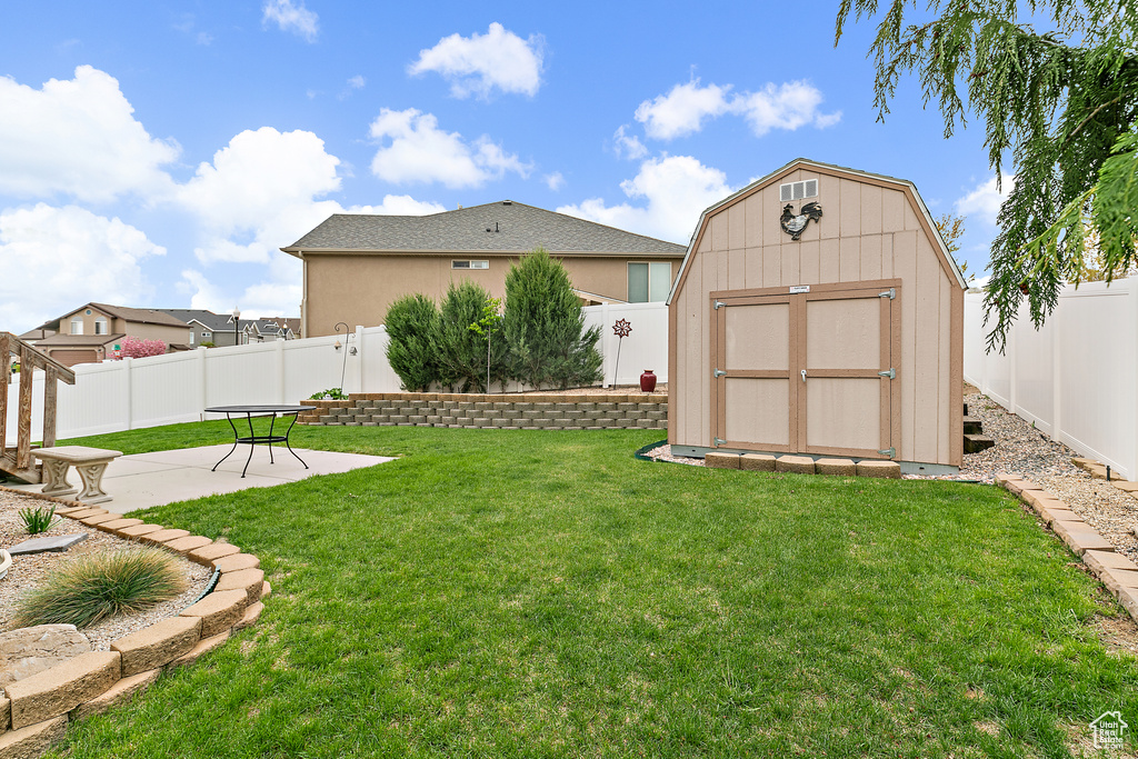View of yard featuring a storage shed, a patio, and a fenced backyard