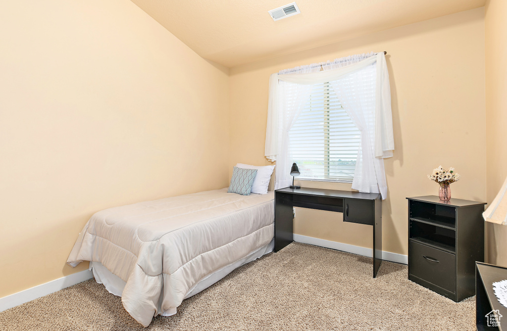 Bedroom featuring visible vents, light carpet, and baseboards