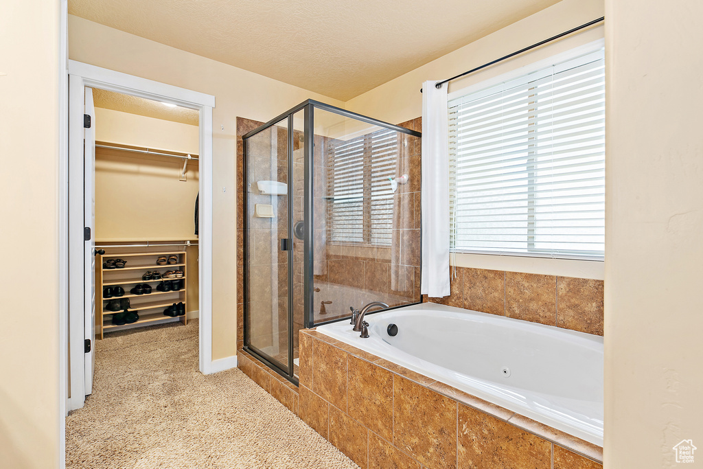 Full bath with a stall shower, a walk in closet, and a bath