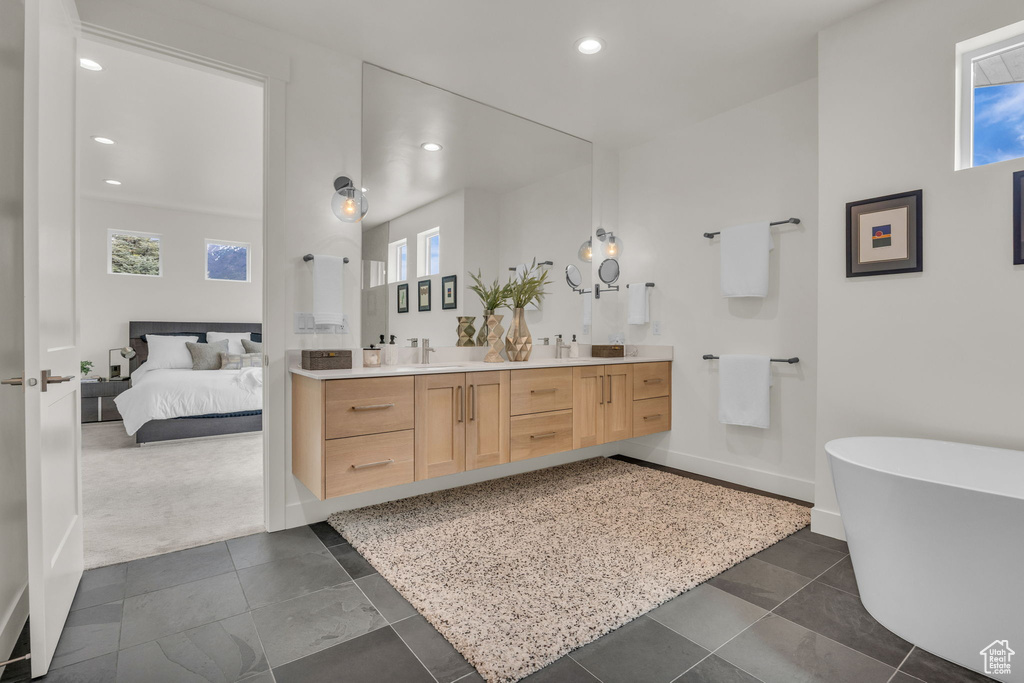 Ensuite bathroom featuring recessed lighting, double vanity, a healthy amount of sunlight, and a soaking tub