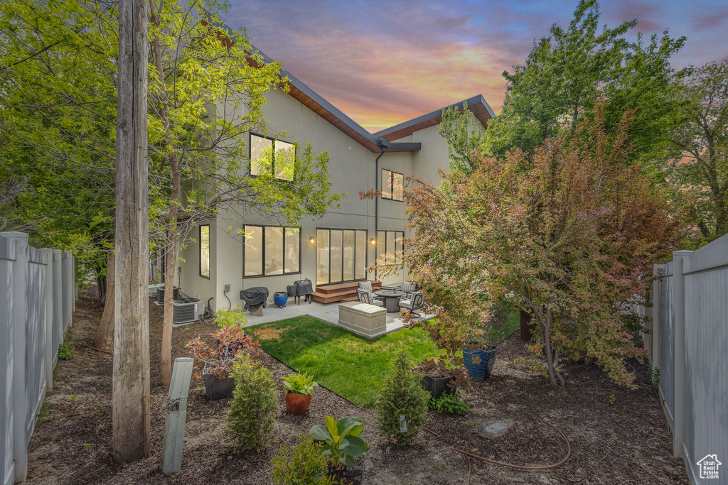 Back of house at dusk with a patio, a fenced backyard, and stucco siding