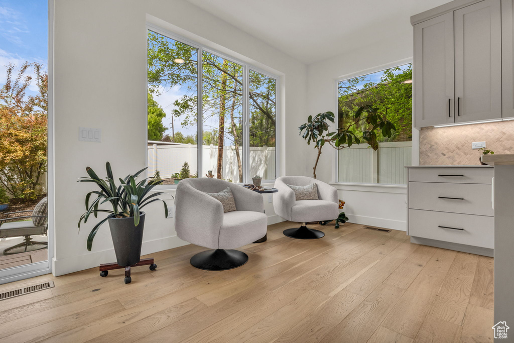 Sitting room with baseboards, light wood finished floors, and visible vents