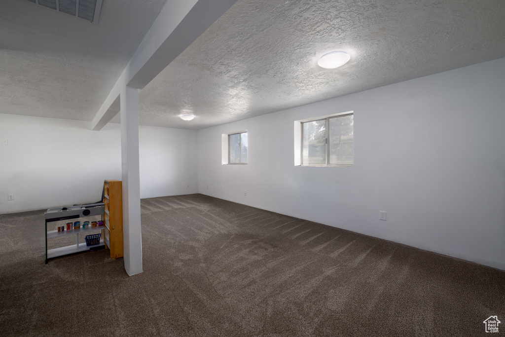 Basement featuring carpet floors, a textured ceiling, and visible vents
