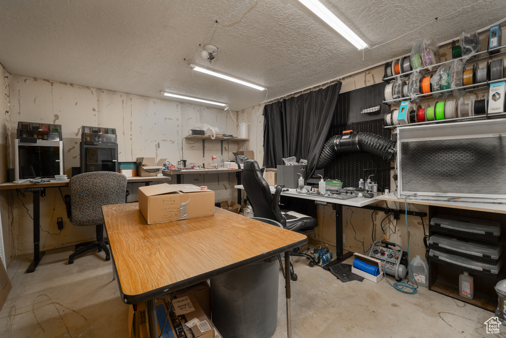 Home office with a workshop area, concrete flooring, and a textured ceiling